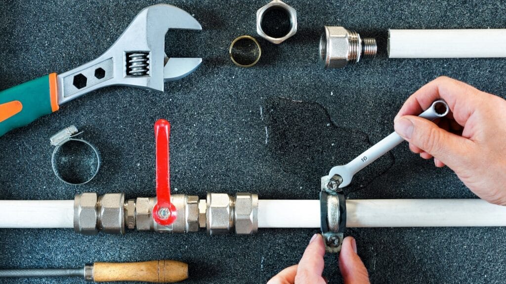 Plumber repairing a pipe valve with an adjustable wrench in Villa Rica