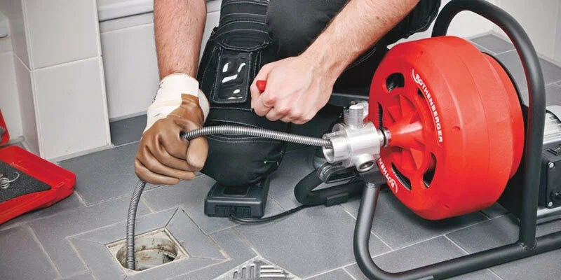 Plumber using a drain-cleaning machine in Villa Rica