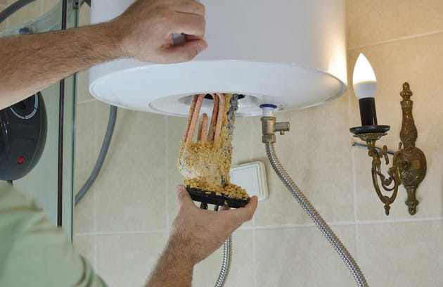 Technician removing mineral buildup from a water heater in Villa Rica