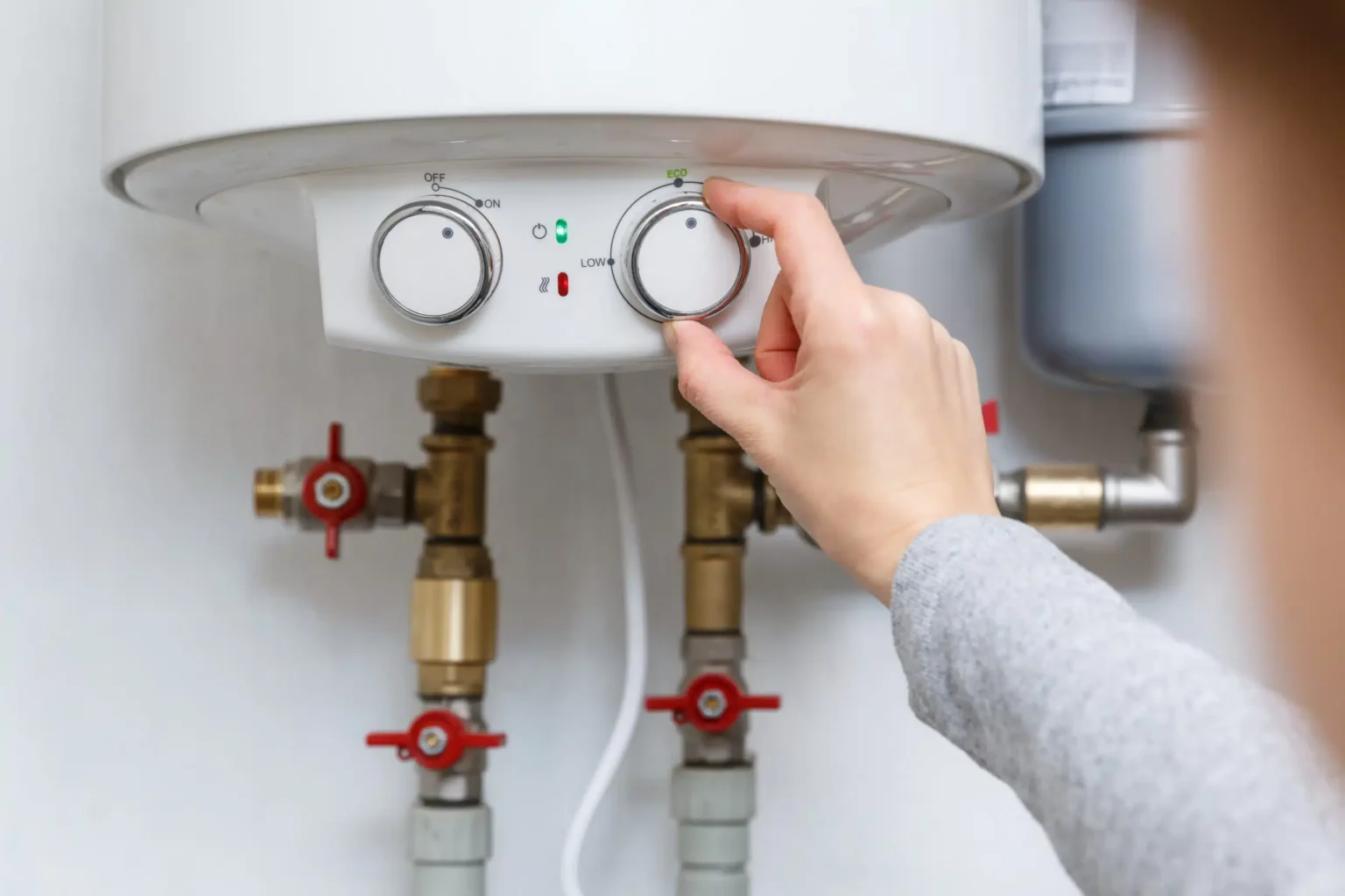 Homeowner adjusting the temperature controls on a water heater in Villa Rica